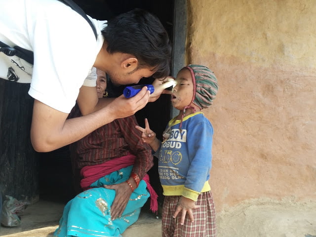 Ophthalmic health worker examining child eyes during trachoma survey